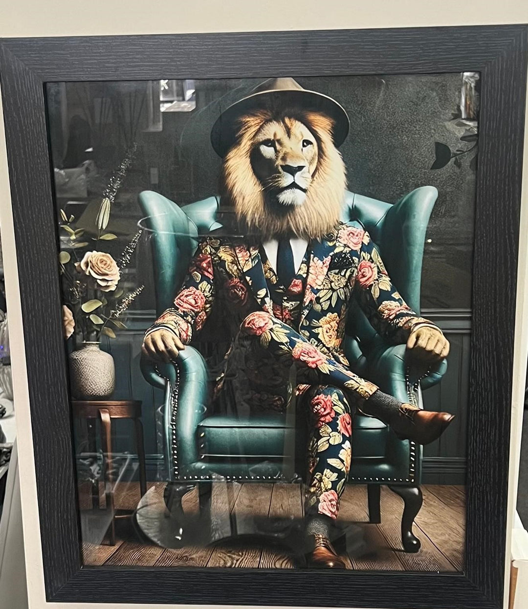 Black framed picture of lion in a black floral suit & hat wall art