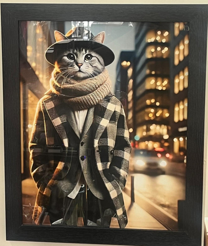 Black framed picture of a cat wearing beige coat, scarf & hat wall art decor
