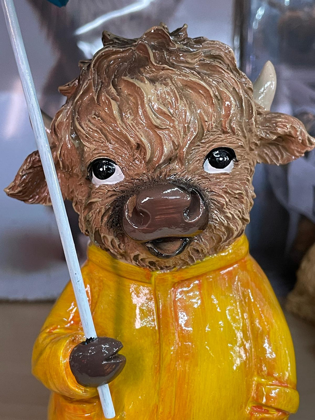 Highland cow in the rain with a blue umbrella yellow rain coat decor ornament