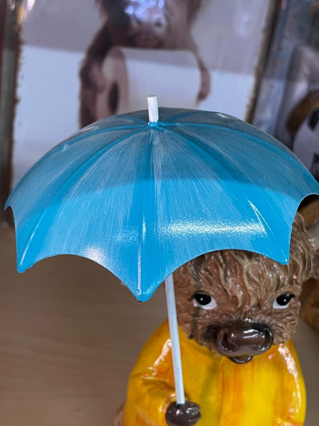 Highland cow in the rain with a blue umbrella yellow rain coat decor ornament