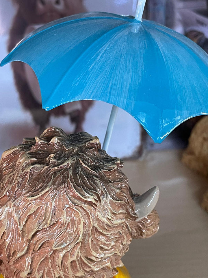 Highland cow in the rain with a blue umbrella yellow rain coat decor ornament